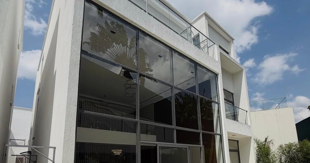 Contemporary white villa exterior with double-height glass facade and roof terrace, designed by Epique Interiors