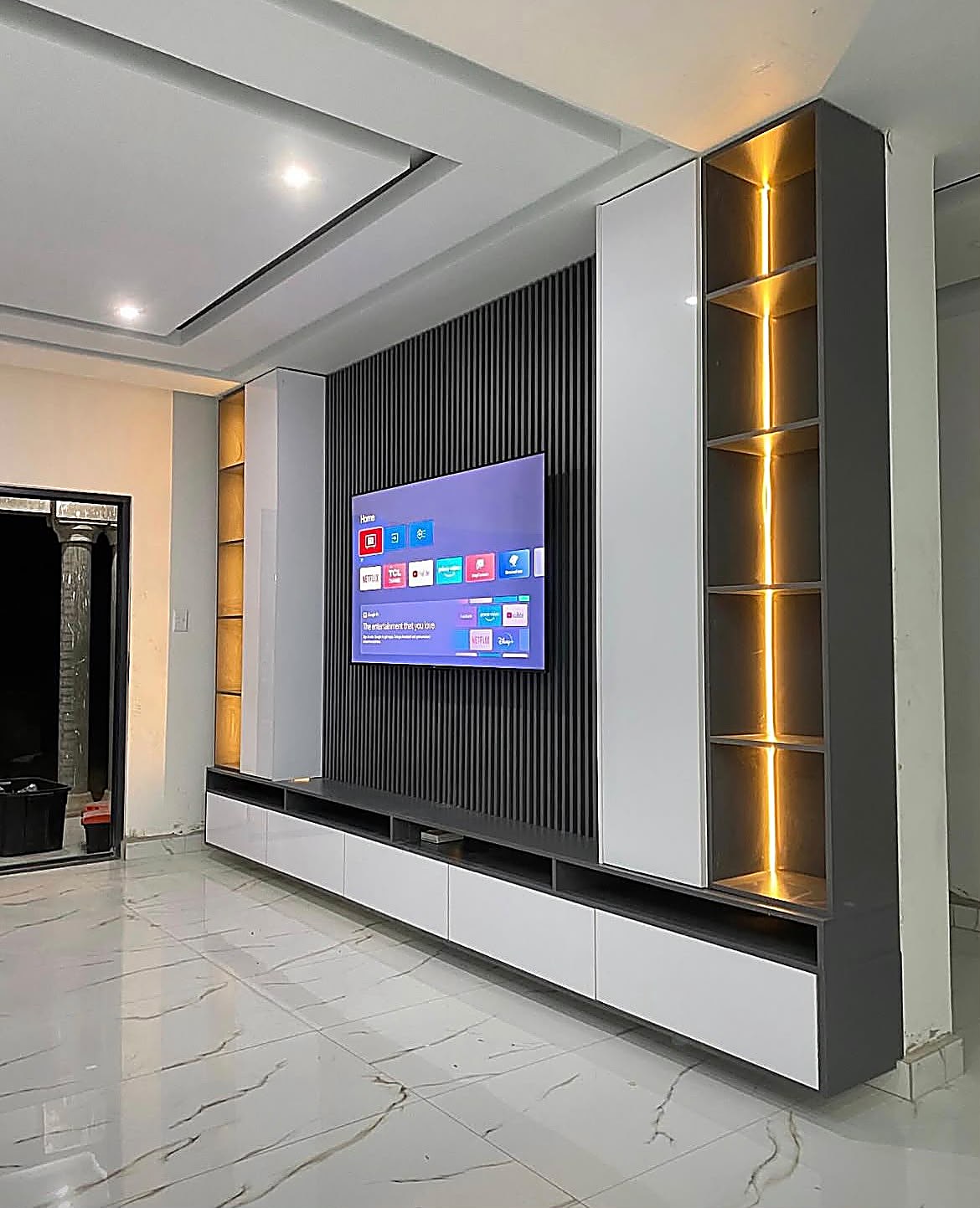 TV Units — Bespoke wall-to-wall TV unit with fluted panel, white gloss cabinets and LED-lit display shelving — custom furniture for Kenyan homes by Epique Interiors.