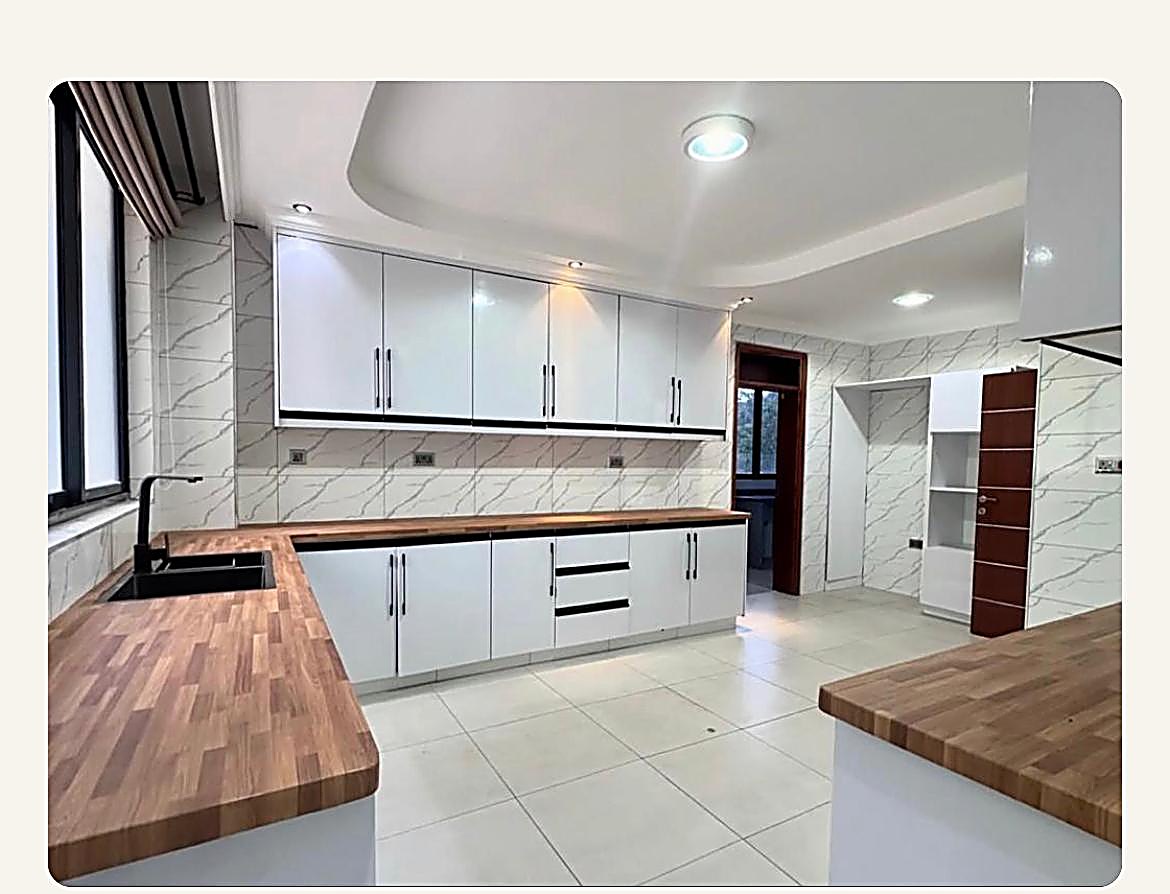 Karen Brooks Estate — White gloss kitchen with wood-block worktops, marble-look wall tiles and a coffered ceiling at Karen-Brooks Estate, Nairobi, by Epique Interiors.