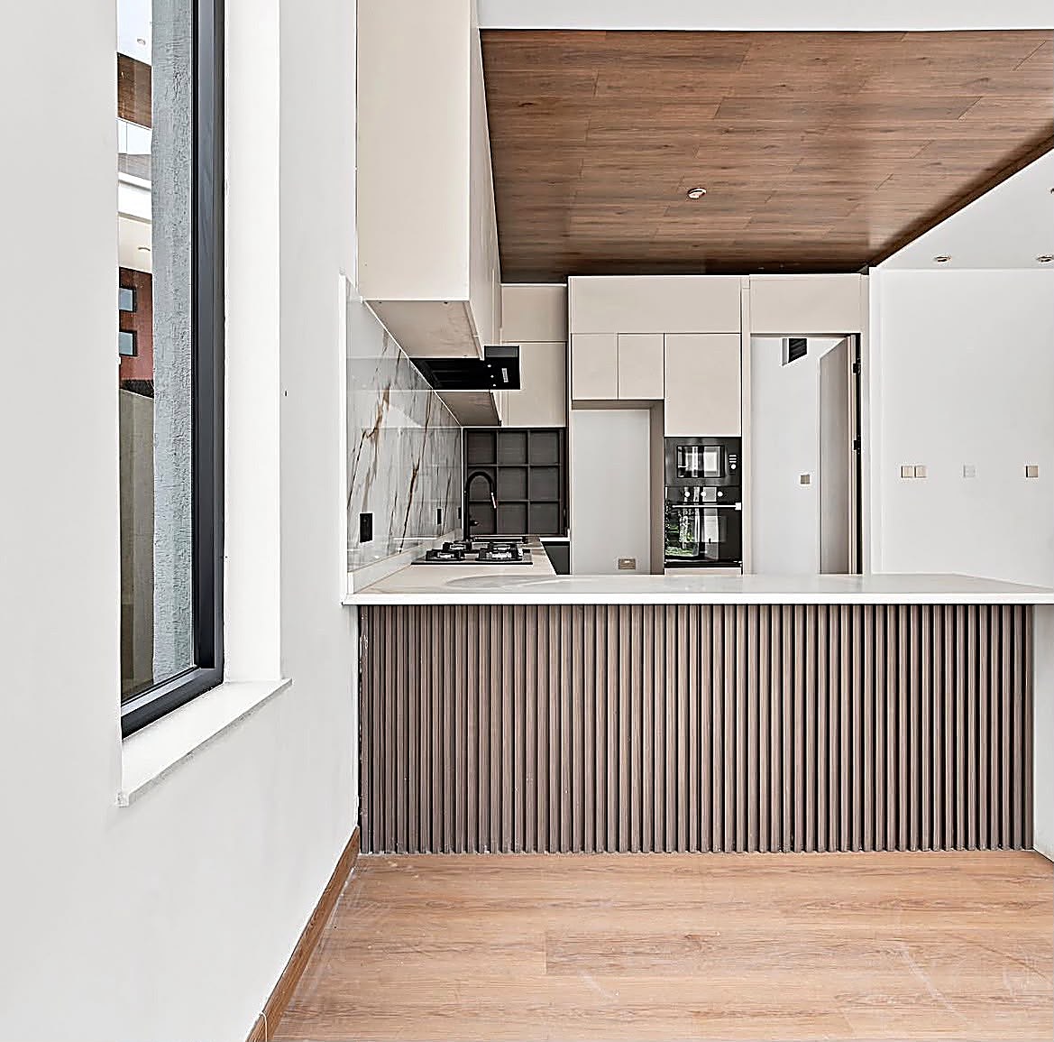 Limuru Project — Kitchen with cream cabinetry, marble splashback and fluted wood breakfast bar in a Limuru home — interior design and joinery by Epique Interiors.