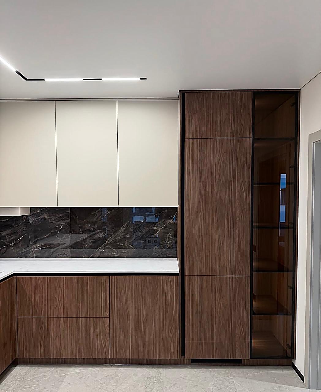 Riverside Drive Westlands — Handleless cream and walnut kitchen with dark marble splashback and glazed display cabinet on Riverside Drive, Westlands, by Epique Interiors.